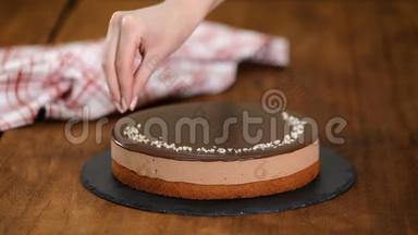 女人<strong>装饰</strong>和洒坚果在上面的<strong>巧克力慕斯</strong>蛋糕。